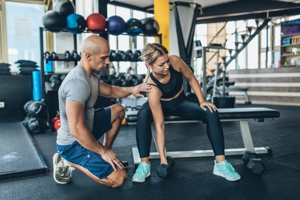 personal trainers in San Diego, CA  professional male fitness trainer guiding a determined female